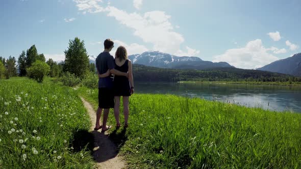 Couple standing with arm around watching beautiful mountain ranges4k