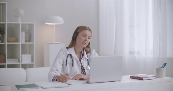 Female Doctor Is Chatting with Patients or Colleagues By Video Call on Laptop, Working Remotely