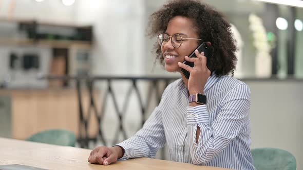 Cheerful African Businesswoman Talking on Smartphone in Office