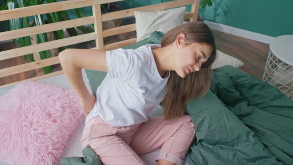 Young Woman Feels Back Pain on the Bed at Home Rubs Her Lower Back Poor Sleep