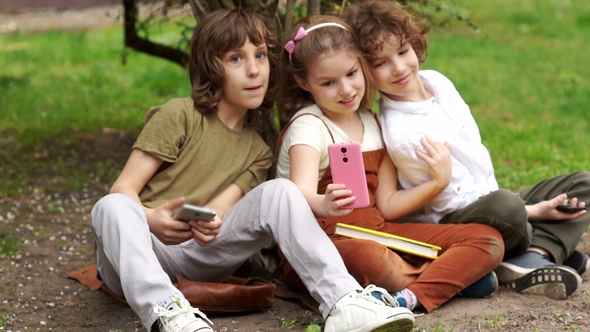 Students Sit on the Grass During a School Break and Take a Selfie. Two Boys and a Girl, School
