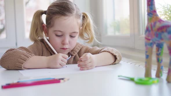 Child with paper and pencil sitting on chair