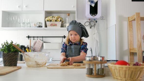 Preschool Girl Baker Puts Biscuits on a Baking Sheet