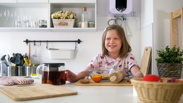 Little Girl Laughing on the Kitchen with Brewing Teapot