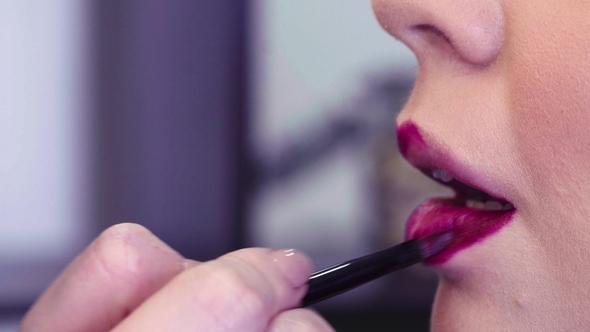 Makeup Artist Applying Pink Lipgloss on the Lips