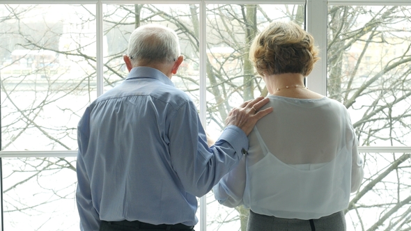 Elderly Couple Embracing and Kissing at the Window