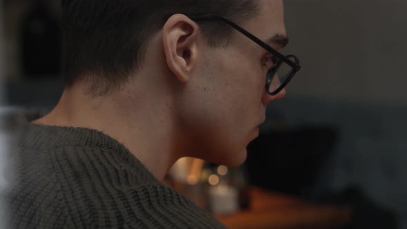 Serious man wearing eyeglasses sitting in cafe