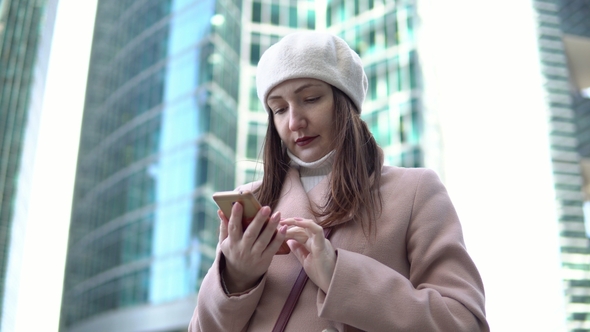 Young Woman with the Phone Among the Tall Buildings of a Megacity