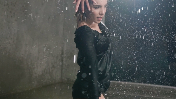 A Young Caucasian Girl Performs a Modern Dance Barefoot in the Water Under the Rain Drops at Studio