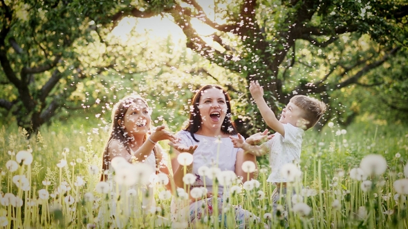 Happy Mother and Kids Playing with Dandelions