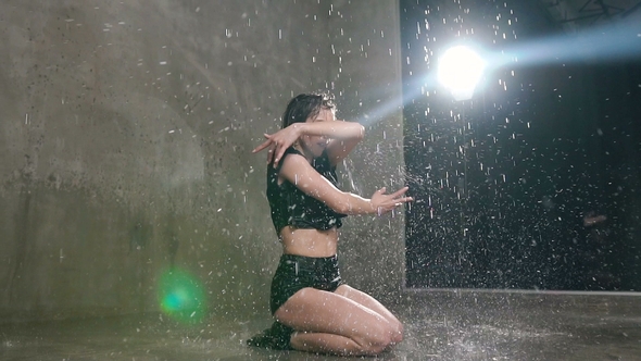Wet Girl Dancer in Black Body Performs Contemporary Dance on the Floor in the Rain and Splashes