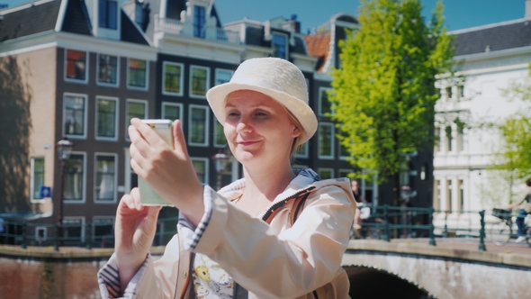 A Woman Tourist Takes Pictures of Herself in a Picturesque Place Near the Canal. Tourism in the