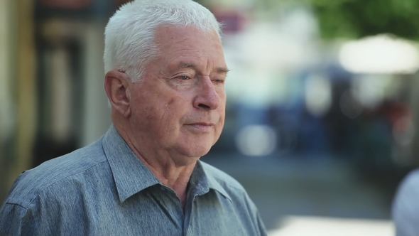 Brave Grey-headed Man Stands in a Green Street and Thinks on a Sunny Day