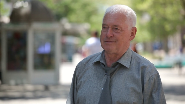 Happy Senior Man Stands, Smiles and Raises Two Thumb Up Gestures in a Street