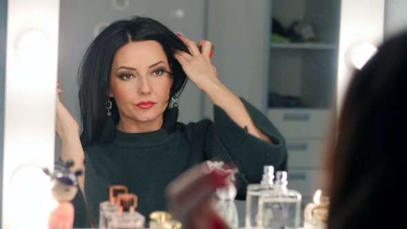 Beautiful Mature Woman Looking at Herself in Mirror Checking Face with Makeup