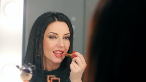 Reflection of Lady Applying Her Make-up. Brunette Mature Woman Putting Lipstick