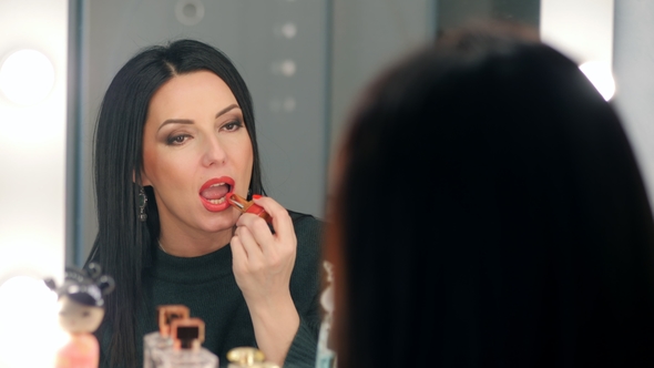 Reflection of Lady Applying Her Make-up. Brunette Mature Woman Putting Lipstick While Looking in