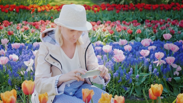 Young Woman Tourist Taking Pictures of a Beautiful Flowerbed with Flowers in Keukenhof Park in the