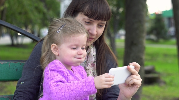 Mother and Cute Little Daughter Taking Selfie with Smartphone in the Park