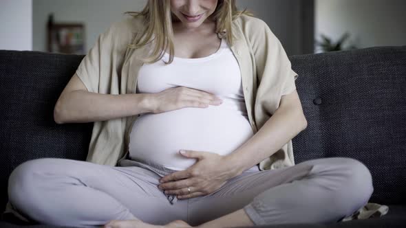 Front View of Pregnant Woman Massaging Belly and Talking