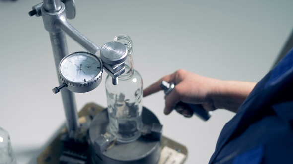 Factory Worker Is Checking Size Parameters of a Glass Bottle