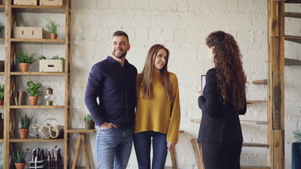 Young People Are Talking with Housing Agent and Hugging Standing Inside Loft Style House