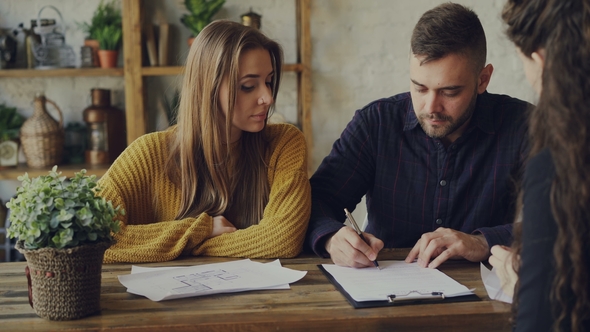 Handsome Man House Buyer Is Signing Sales Agreement with Housing Agent, Getting Key and Hugging