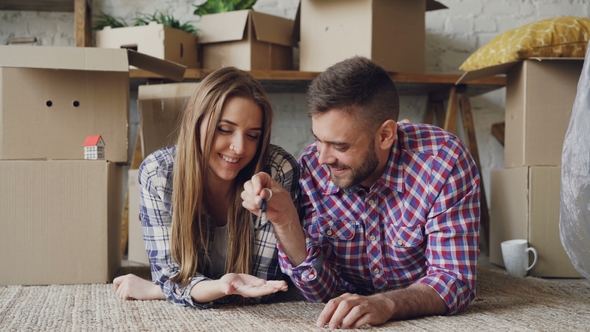 Cheerful Bearded Guy Is Giving Key To His Girlfriend and Kissing Her Lying on Floor of New Flat
