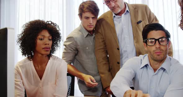 Businessman and coworkers discussing over laptop at desk