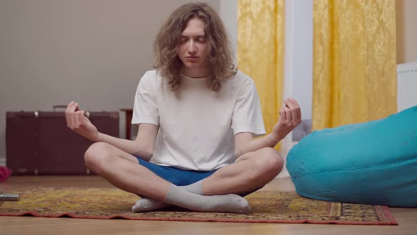 Young 80s Styled Man Meditating in Lotus Pose at Home
