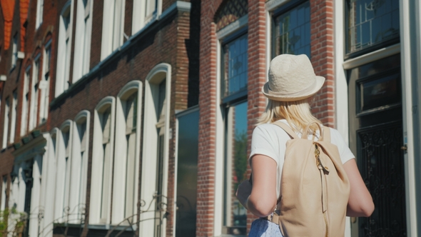 A Young Woman with a Pink Backpack Enjoys a Stroll Through the Ancient Street of the European City