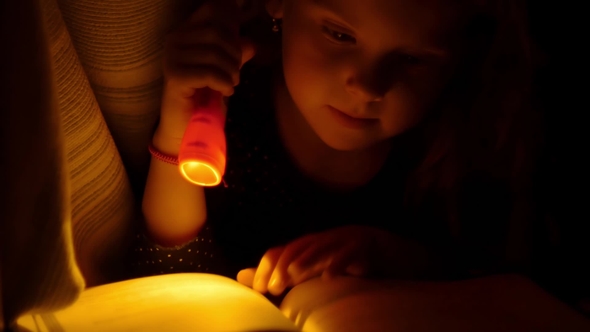 Kid Reading In Bed with a Flashlight