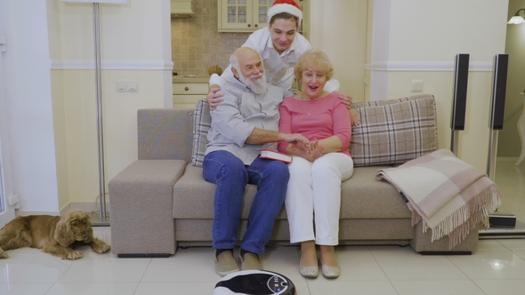 Grandson in Santa's Hat Hugs Grandparents