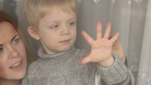 Little Boy Is Holding His Palm on Window,