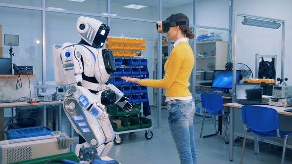 Robotic Humanoid Is Putting Its Hands Onto the Hands of a Young Woman