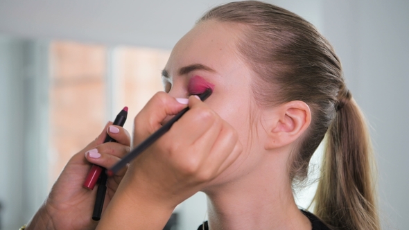 Makeup Artist Applying Makeup Products on a Beautiful Model in Studio before Photoshooting