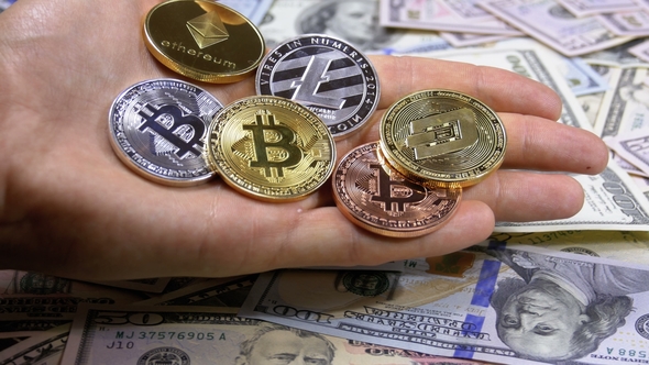 Hand Holds Different Coins of Cryptocurrency on a Table with US Dollars Are Rotating