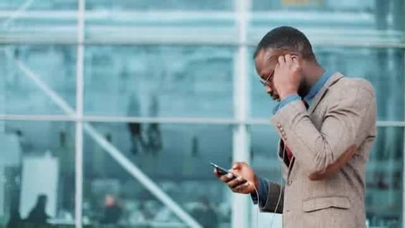 African American Businessman Listens to the Music and Dances while He Walks near the Office Building