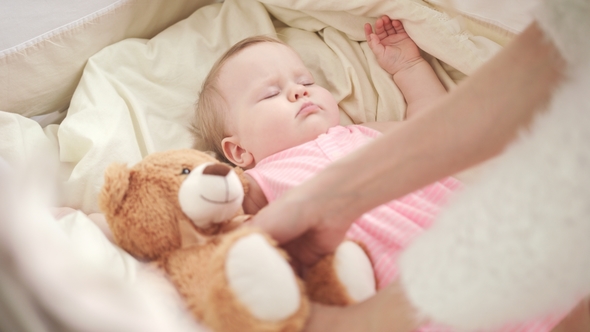 Mother Putting Toy To Sleeping Baby in Cot. Adorable Baby Sleep in Crib