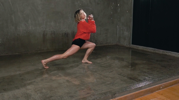 A Professional Dancer Performs a Modern Dance Under the Water Rain on Stage in Front of a Studio