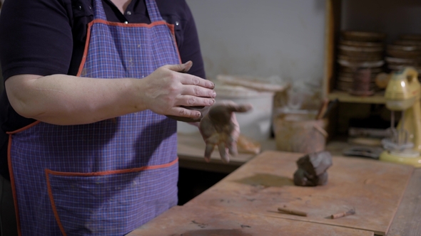 Crop Hands of Master of Pottery Rolling Out Clay for Creating Earthenware in Workshop