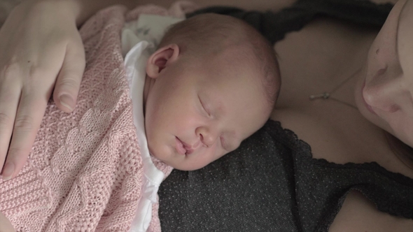Mother Stroking Beloved Newborn Daughter Sleeping on Her Chest