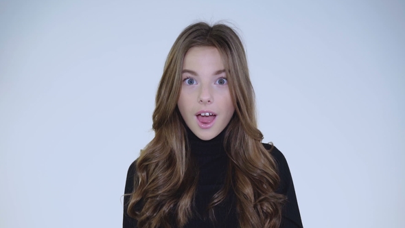 Portrait of Surprised Girl Corrects Her Hair and Nods Head at Camera