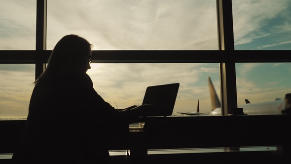 Silhouette of Business Woman in Suit, Working with Laptop in Airport Terminal