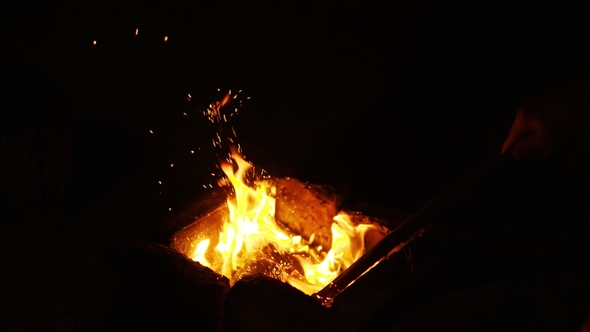 Fire Sparks Moving on Dark Black Background Coming from Brightly Burning Warm