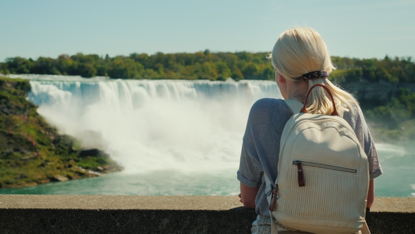 A Tourist with a Backpack Behind Him Looks at Niagara Falls. Rear View, Taken From the Canadian