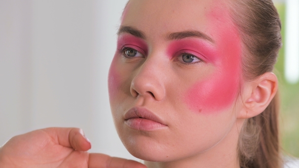 Makeup Artist Making Beautiful Face Art for Young Blonde Woman with Makeup Brush