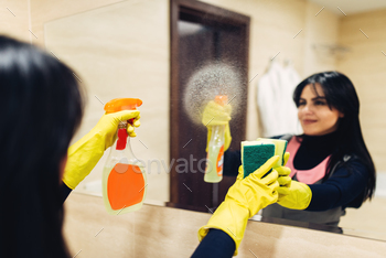  with a cleaning spray, hotel bathroom interior on background. Professional housekeeping service, charwoman, sanitary processing