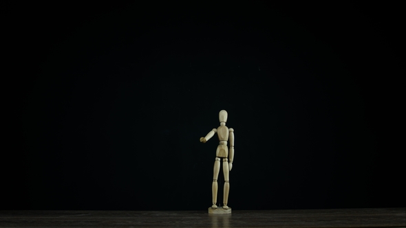 Wooden Figure Dummy Waving Arm in Studio on Black Background, Showing Goodbye