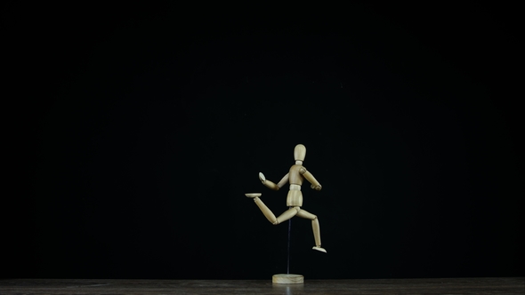 Running Wooden Figure Dummy in Studio on Black Background Rotates with Freezed Motion